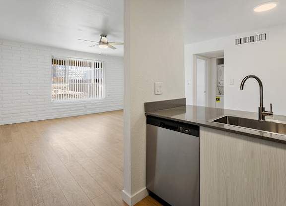 A kitchen with a stainless steel dishwasher and a black trash can.