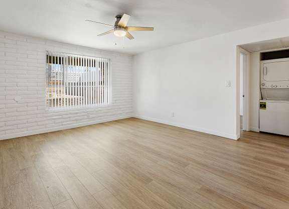 A room with a ceiling fan and wooden flooring.