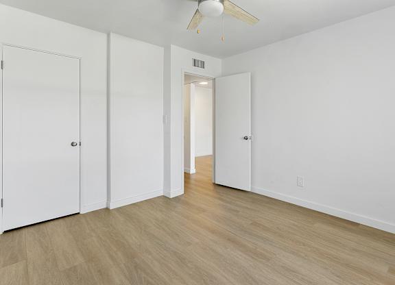 A room with a ceiling fan and white walls.