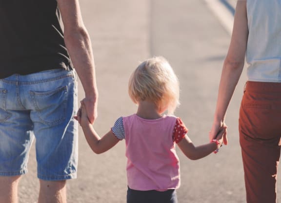 a family holding hands while walking down a road