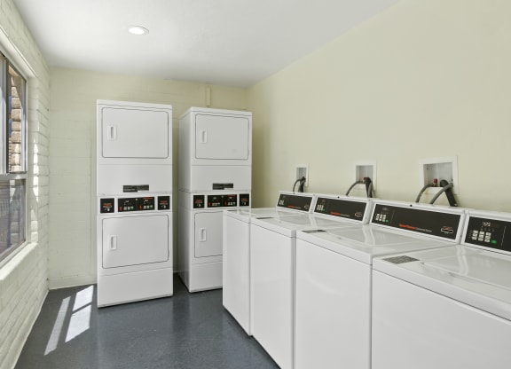 a laundry room with white washers and dryers