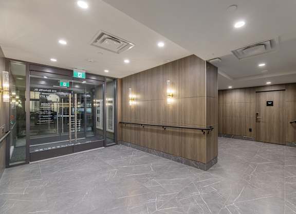 A hallway with a glass door and a green exit sign above it.