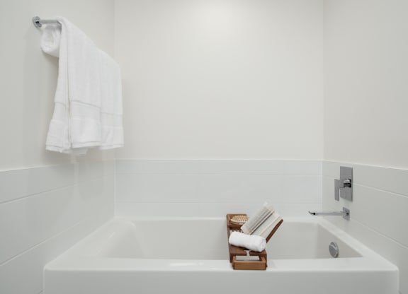 a white bathroom with a bath tub and a towel