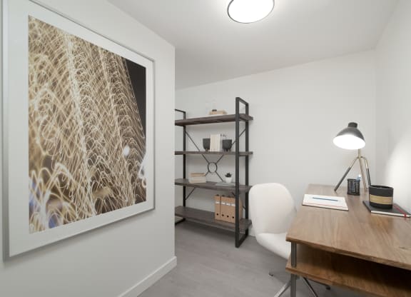a home office with a large picture on the wall and a wooden desk