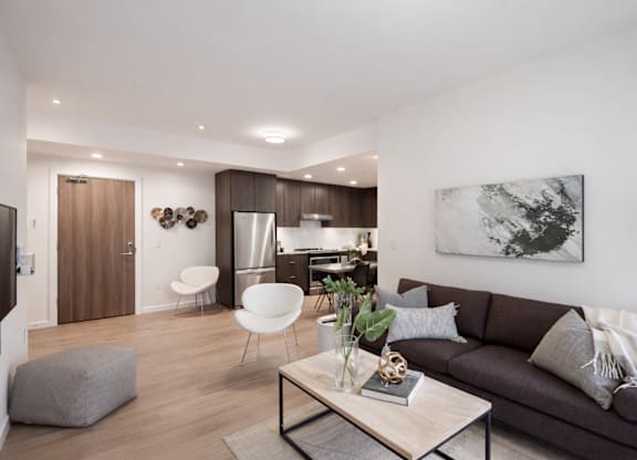 A modern living room with a grey couch, a coffee table, and a painting on the wall.