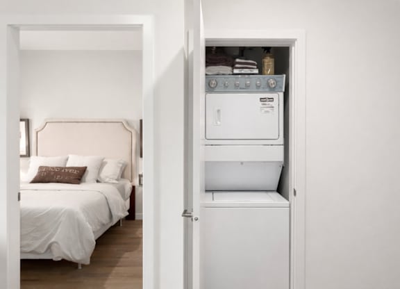 A white bedroom with a bed and a built in cabinet.
