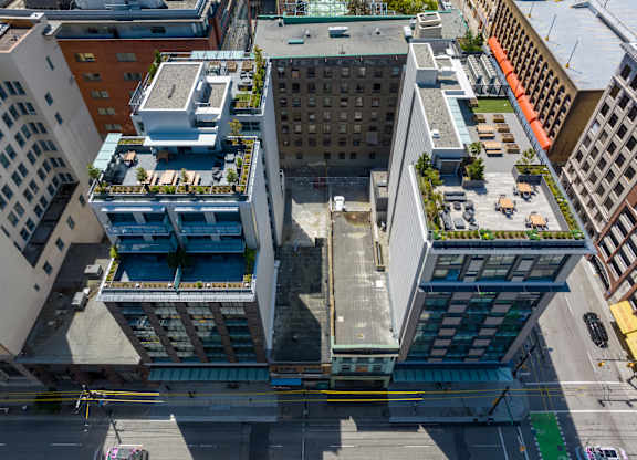 A tall building with a green roof is surrounded by other buildings.