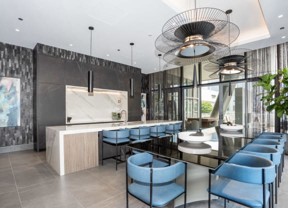 a kitchen and dining area with blue chairs and a long black table
