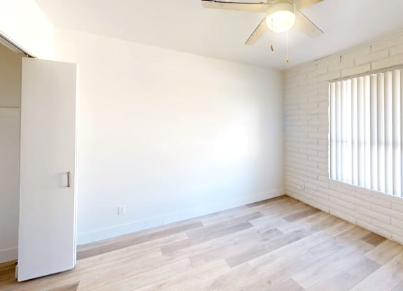 A room with a ceiling fan and a window with blinds.