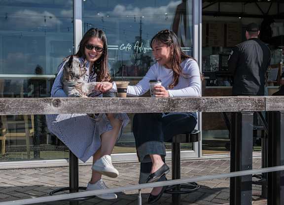 Two women sitting at a table with a dog.