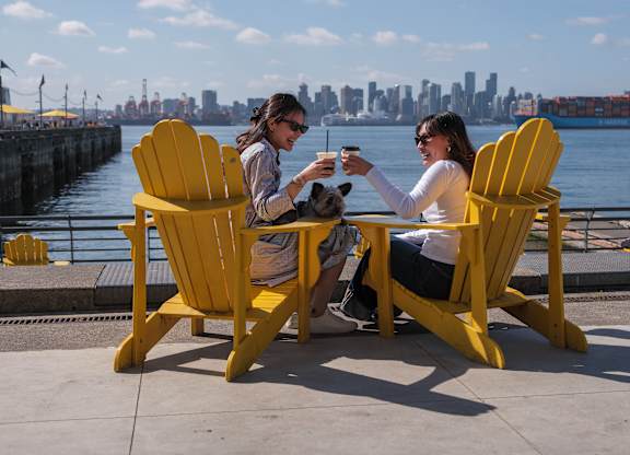 Two people sitting in yellow chairs by the water.