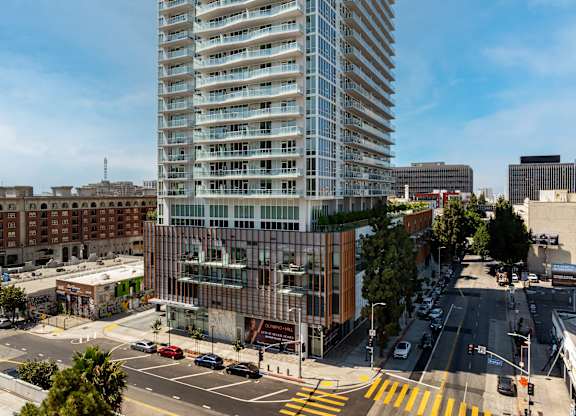 A tall building with many windows is in the middle of a city street.