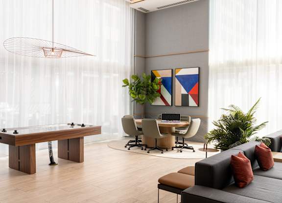 A room with a foosball table, a couch, a desk, and a potted plant.