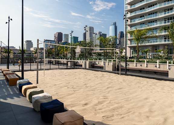 A sandy beach area with benches and a city skyline in the background.