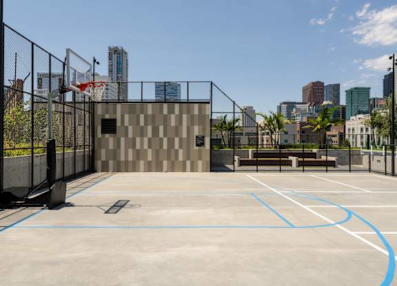 A basketball court with a fence and a building in the background.
