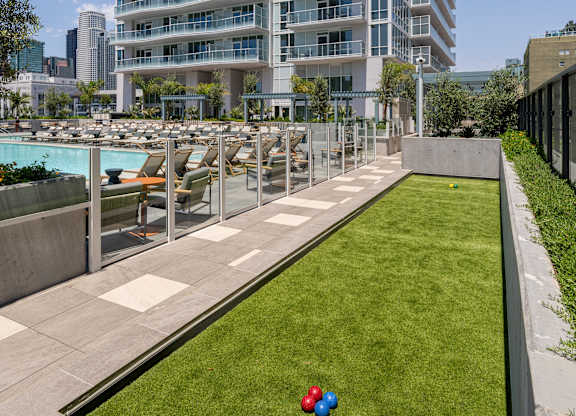 A tall residential building with a pool and a grassy area in front.