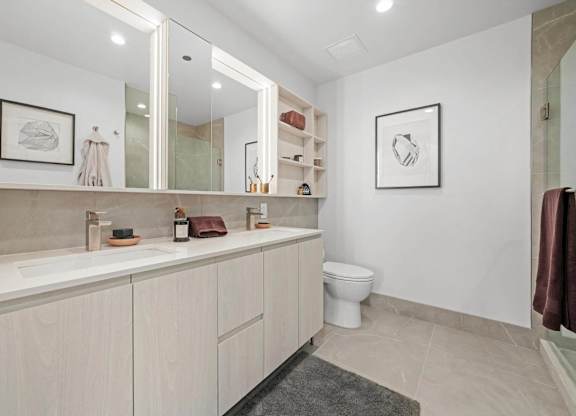 A bathroom with a toilet, sink, and mirror.