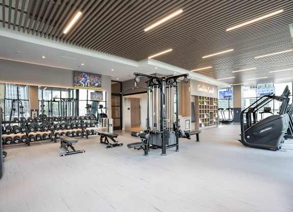 A gym with a variety of equipment including treadmills, weights, and exercise machines.