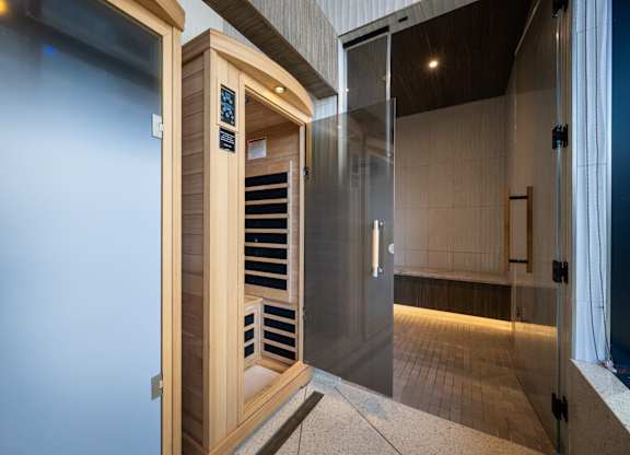 A modern bathroom with a glass door and a wooden cabinet.