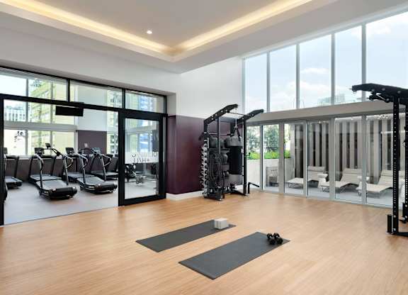 A gym with a variety of equipment including treadmills, weights, and exercise mats.