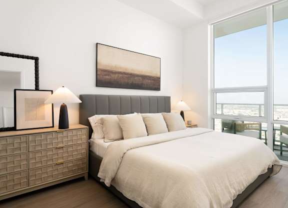A bedroom with a large bed and a painting on the wall.