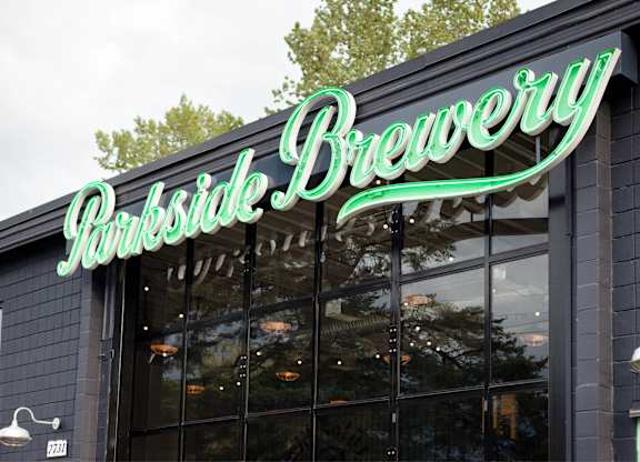 A brewery sign with a green neon light.