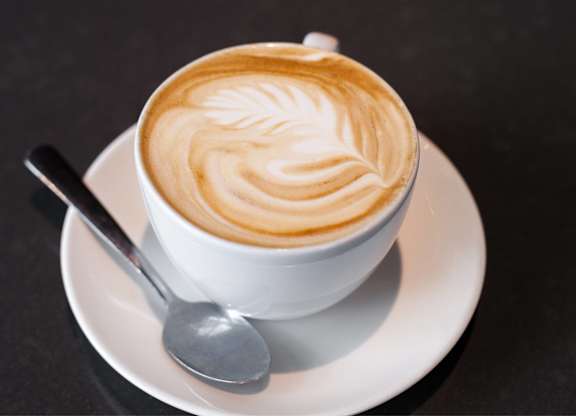 A cup of coffee with a latte art design on top.