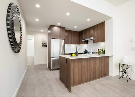 A modern kitchen with wooden cabinets and a large mirror on the wall.