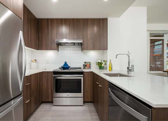 A modern kitchen with a stainless steel refrigerator and wooden cabinets.