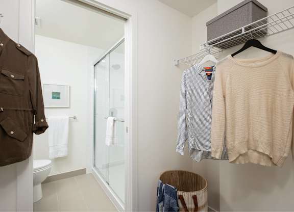 A brown jacket is hanging on a rack next to a white towel.