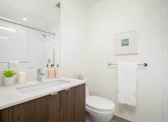 A bathroom with a toilet, sink, and a picture on the wall.