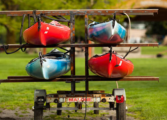 Three kayaks are stacked on a trailer.