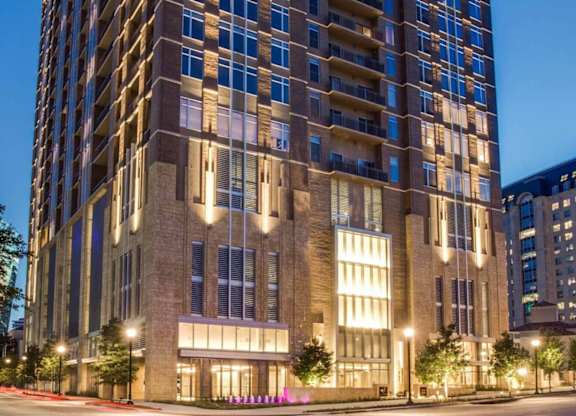 A tall building with many windows is lit up at night.