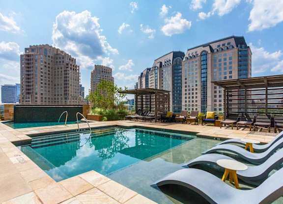 A swimming pool with a modern design is surrounded by a patio area and chairs.