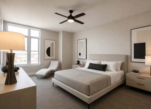 A well-lit bedroom with a large bed, a chair, and a ceiling fan.