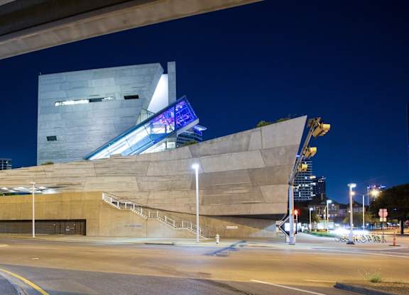 A modern building with a unique design is illuminated at night.