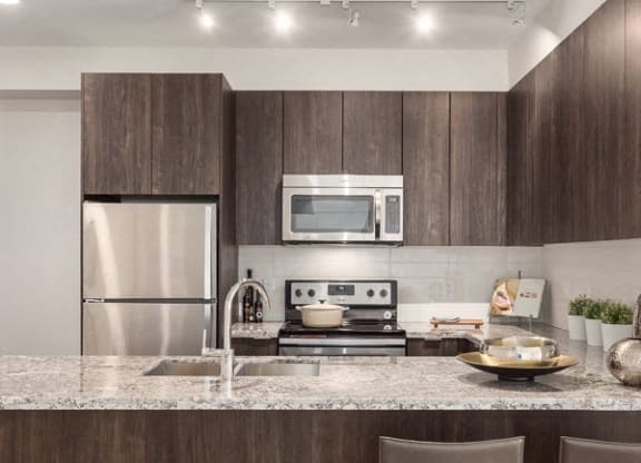 a kitchen with a marble counter top and a stainless steel refrigerator