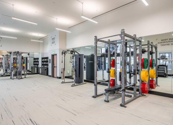 a gym with fitness equipment and mirrors on the wall