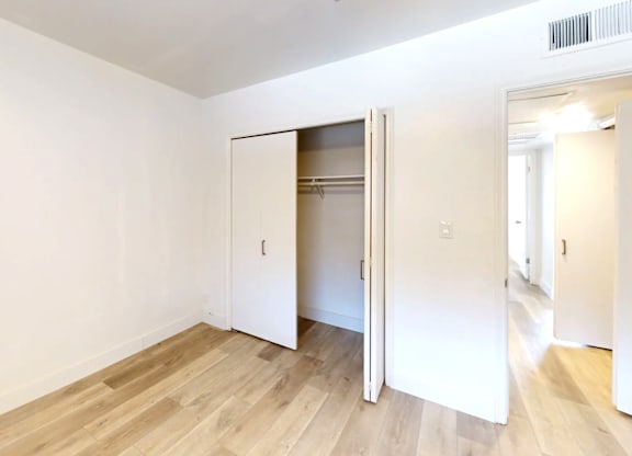 A room with a white wall and a wooden floor with a white door.