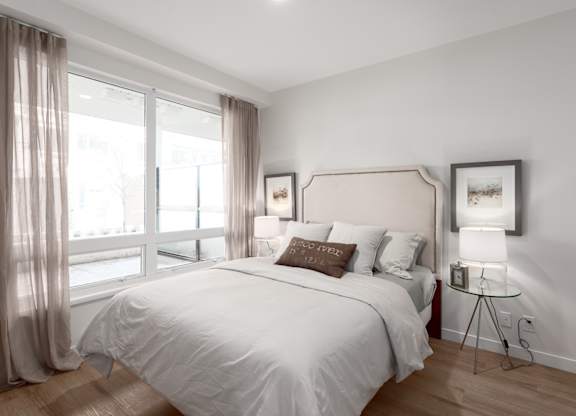 A bedroom with a large bed and a window with curtains.