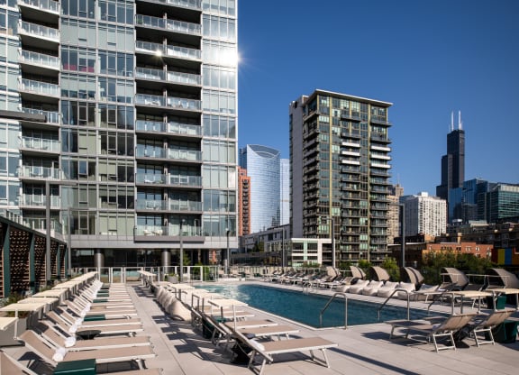 an outdoor pool with lounge chairs next to a tall building in the chicago skyline