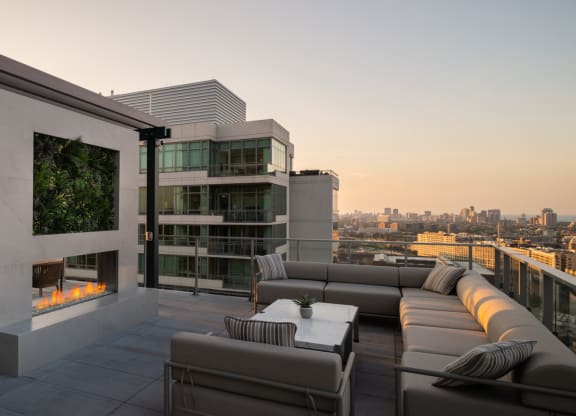 a terrace with couches and a table with chairs and a fireplace