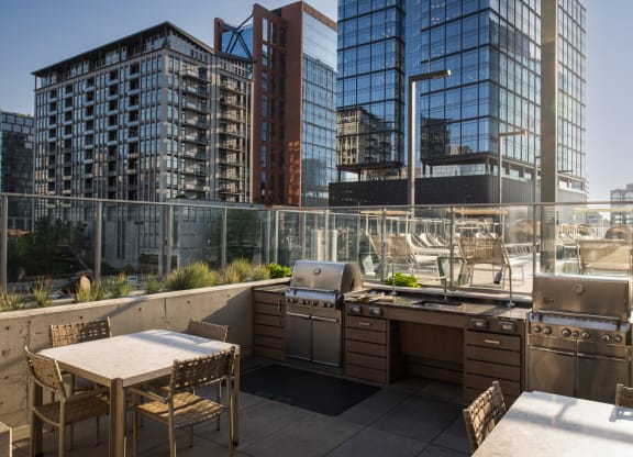 a roof deck with a grill and a table and chairs