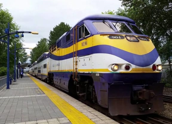 a blue yellow and white train at a train station