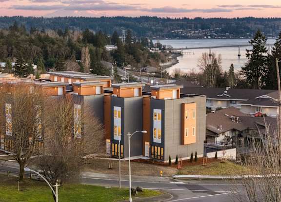 A building with a lot of windows is surrounded by trees. at The Narrows at Clare Apartments , Bremerton, Washington