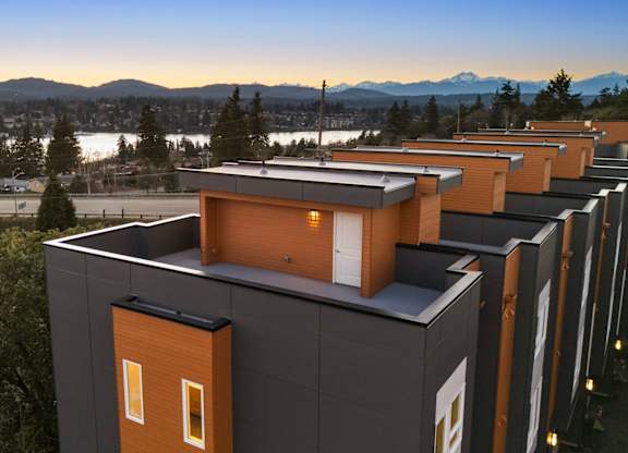 A series of modern houses with orange accents are lined up in a row. at The Narrows at Clare Apartments , Bremerton, WA, 98310