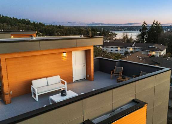 A modern house with a balcony overlooking a lake. at The Narrows at Clare Apartments , Washington