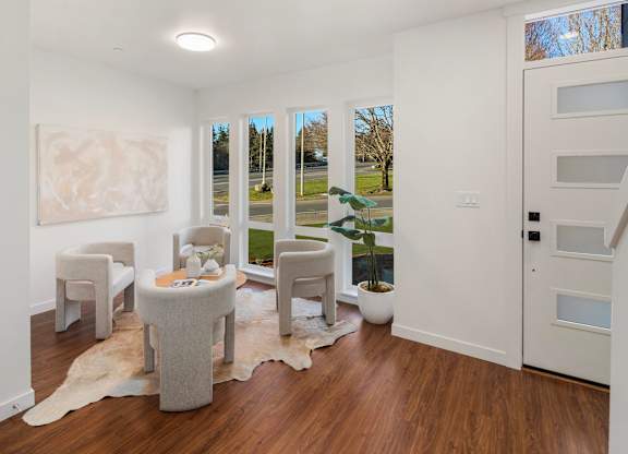 A white room with a table and chairs and a painting on the wall. at The Narrows at Clare Apartments , Apartments, Bremerton, WA