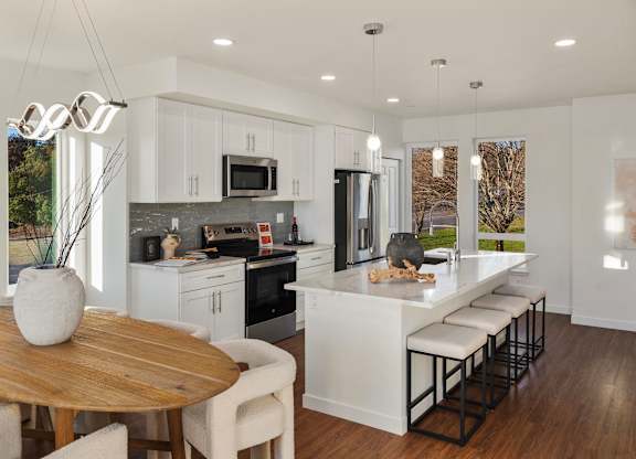 A modern kitchen with a wooden table and white chairs. at The Narrows at Clare Apartments , Bremerton