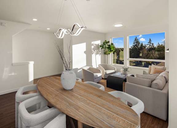 A modern living room with a wooden table and white chairs. at The Narrows at Clare Apartments , Washington, 98310